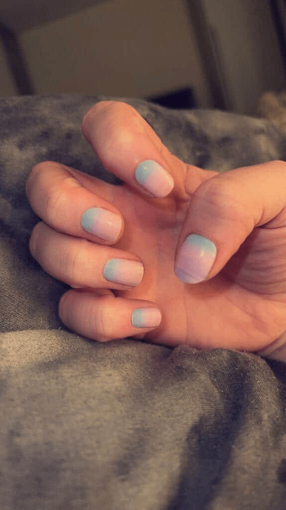 Hands showing pastel gradient nail wraps with blue to pink ombre manicure