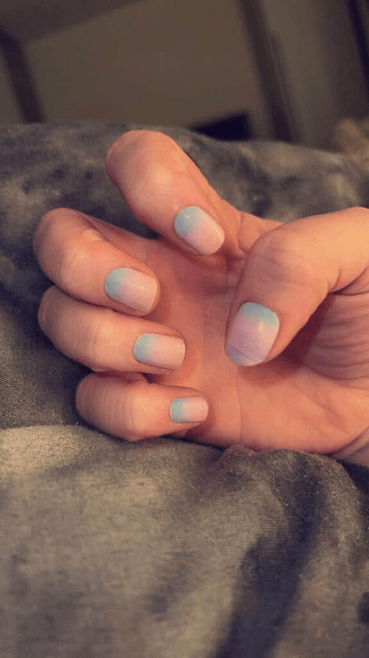 Hands showing pastel gradient nail wraps with blue to pink ombre manicure
