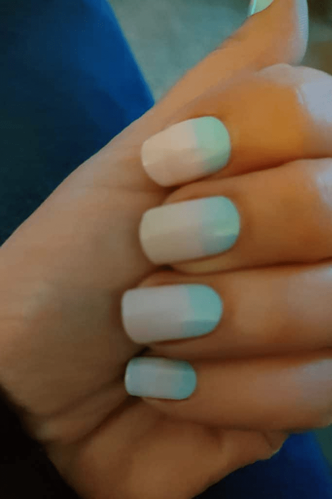 Pastel ombre nail wraps on hand with blue to pink gradient manicure design