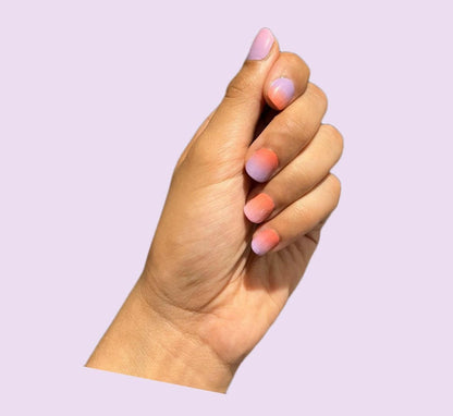 Hand displaying pink coral gradient ombre nail wraps with warm sunset colour transition