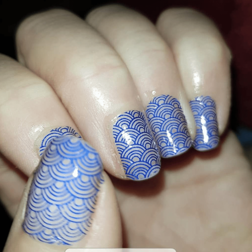 Blue geometric pattern nail wraps with art deco wave design on hand
