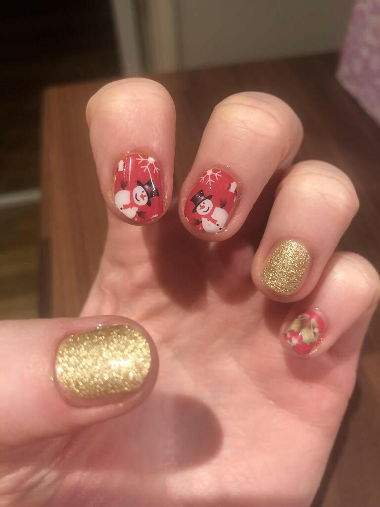 Red Santa Christmas nail wraps with gold glitter accent nails on hand