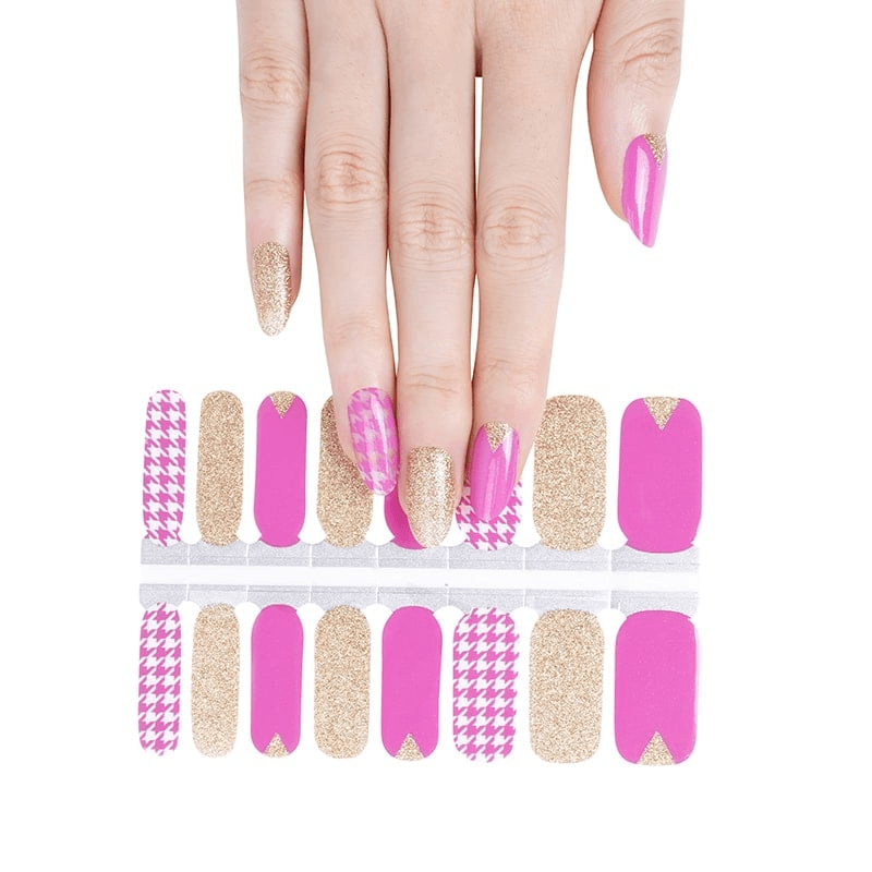 Pink and gold houndstooth nail wraps sheet with hand showing applied manicure design