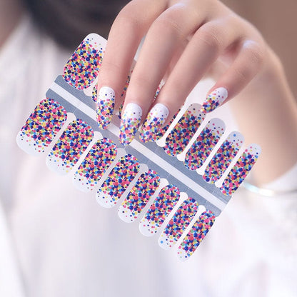 Hand holding multicoloured confetti nail wraps sheet with rainbow polka dot pattern