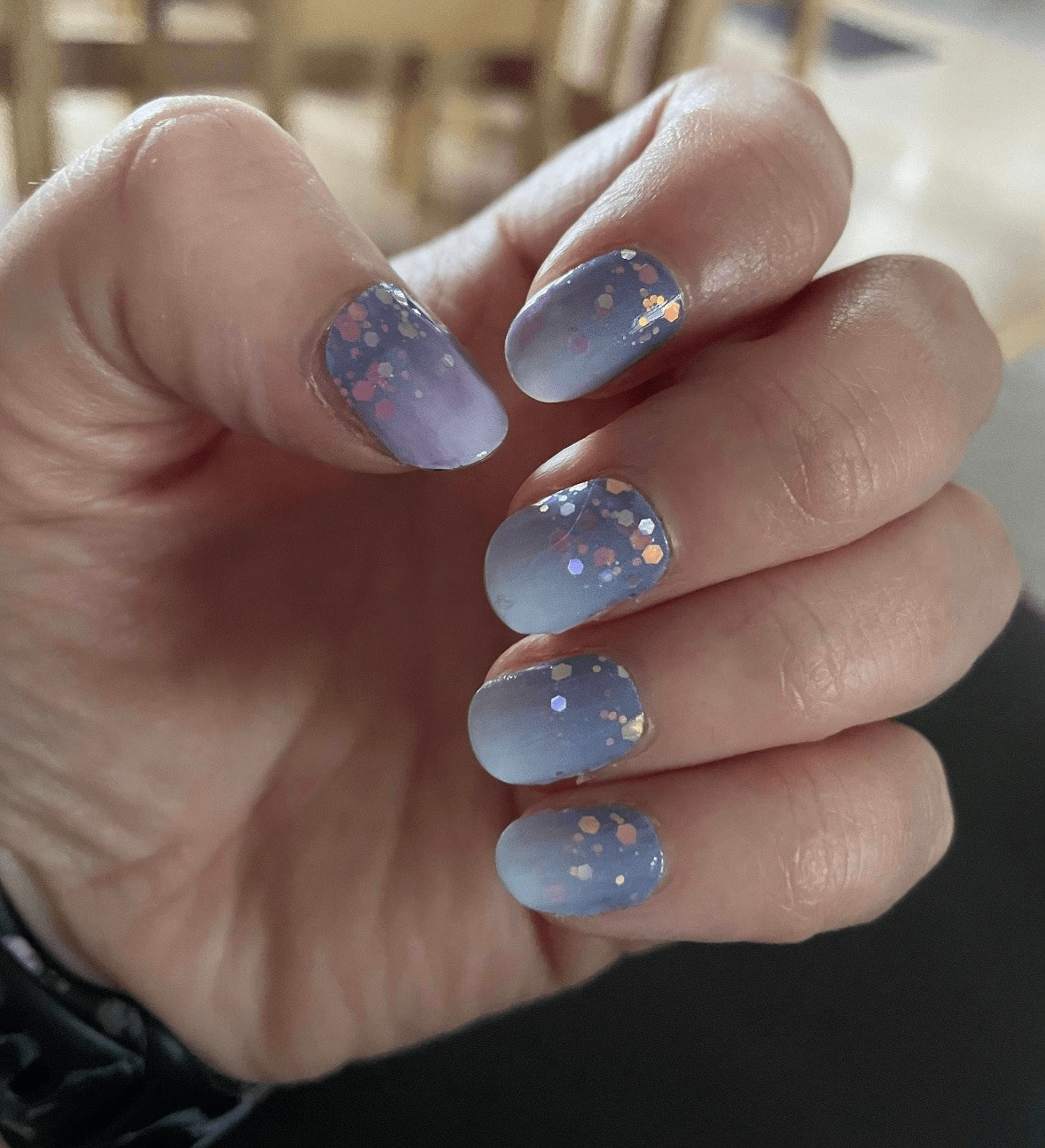 Blue glitter nail wraps applied on hand showing sparkle hexagonal confetti design