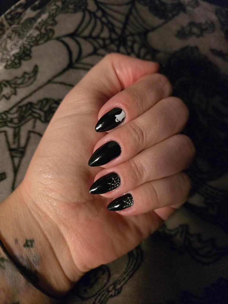 Black Halloween nail wraps featuring white spider and web patterns on almond shaped nails
