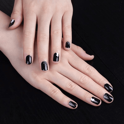 Gothic black nail art with white spider web patterns on extended hands