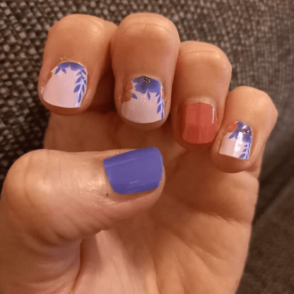Hand displaying mixed manicure with purple coral and floral nail wrap designs