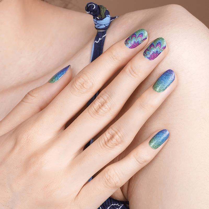 Hand wearing vibrant rainbow gradient nail wraps with psychedelic swirl patterns and floral designs
