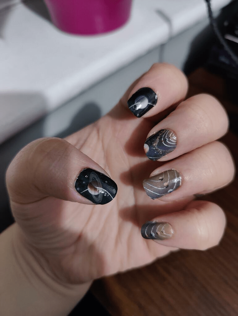 Black and silver chrome nail wraps on hand with metallic geometric patterns for at-home manicure