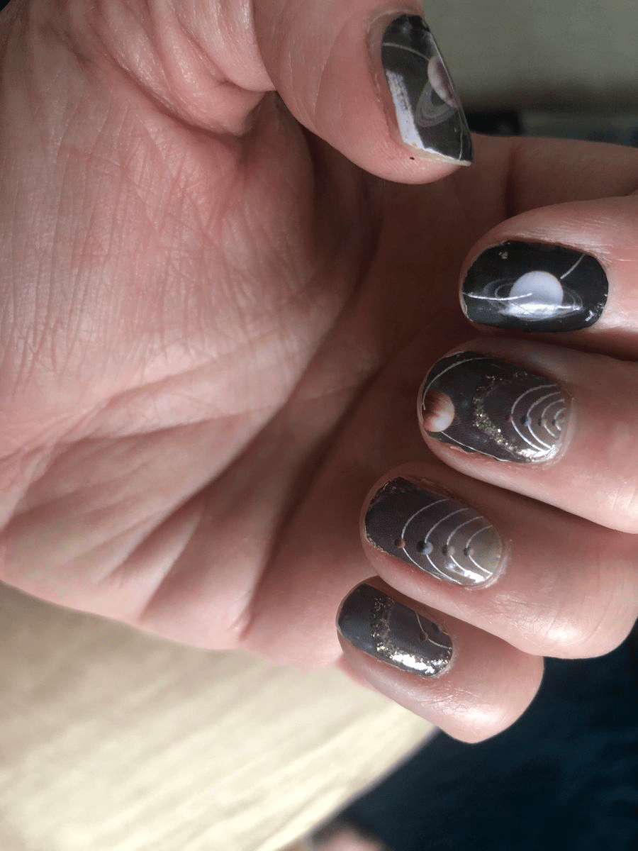 Glossy black nail wraps with chrome silver geometric details on hand showing reflective finish