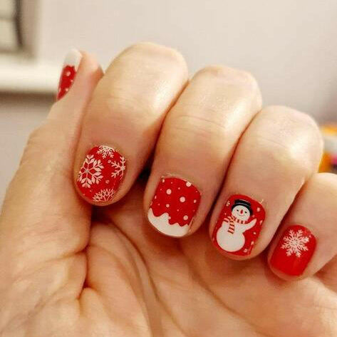 Festive red Christmas nail wraps on hand with snowman and polka dot designs