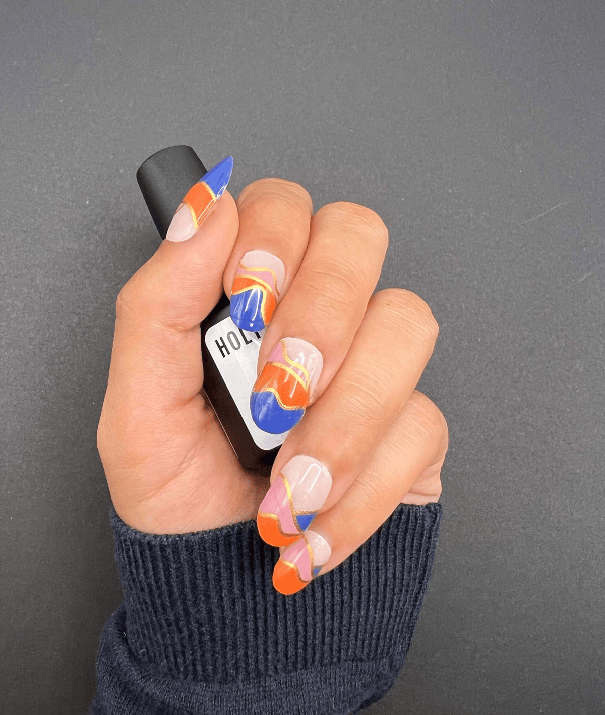 Hand wearing geometric nail wraps with blue orange pink abstract colour block design