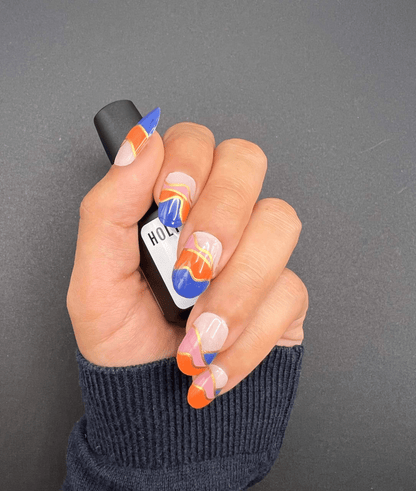 Hand wearing geometric nail wraps with blue orange pink abstract colour block design
