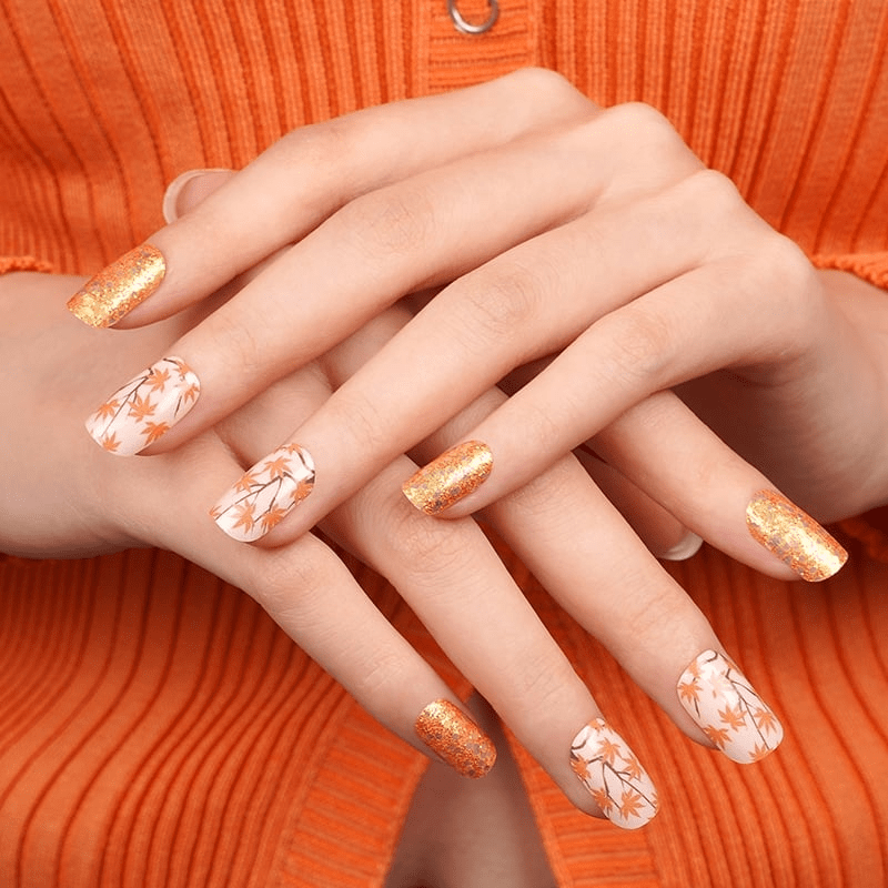 Autumn nail wraps with gold glitter and white maple leaves on hands