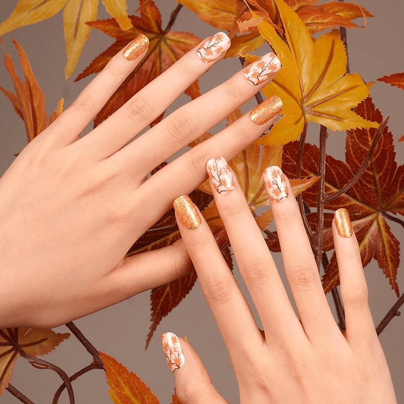 Nail wraps in orange glitter and white with maple leaf branch design
