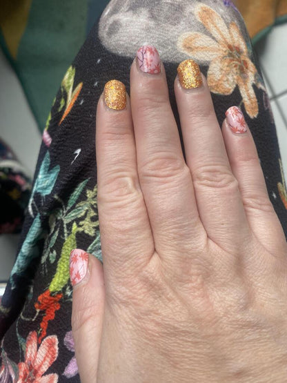 Nail wraps with pink floral maple leaf print alternating with gold glitter accent nails