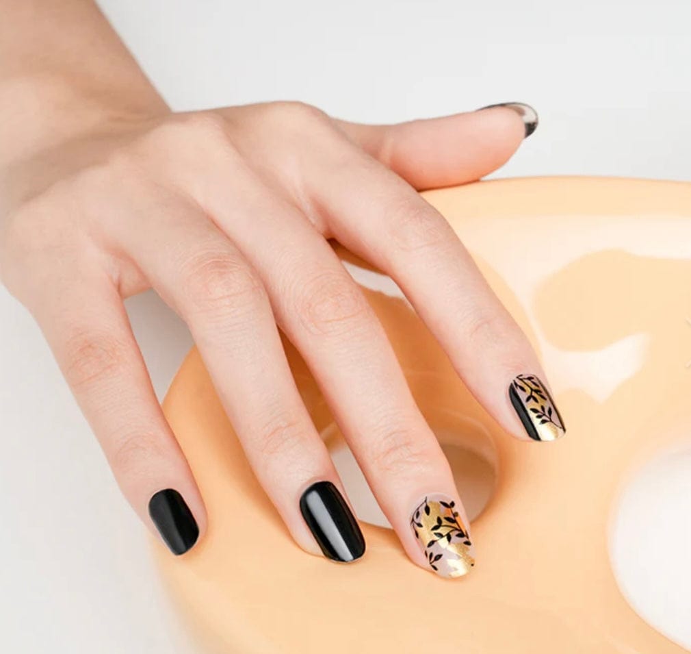 Black and bronze floral nail wraps with botanical pattern on hand
