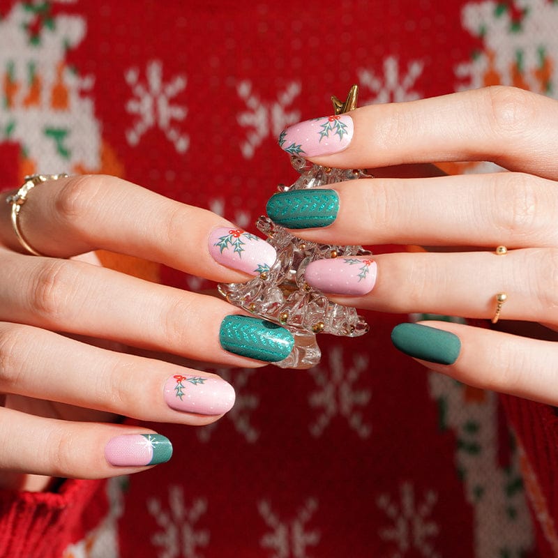 Christmas nail wraps on hands featuring green holly and pink floral patterns with festive holiday nail art