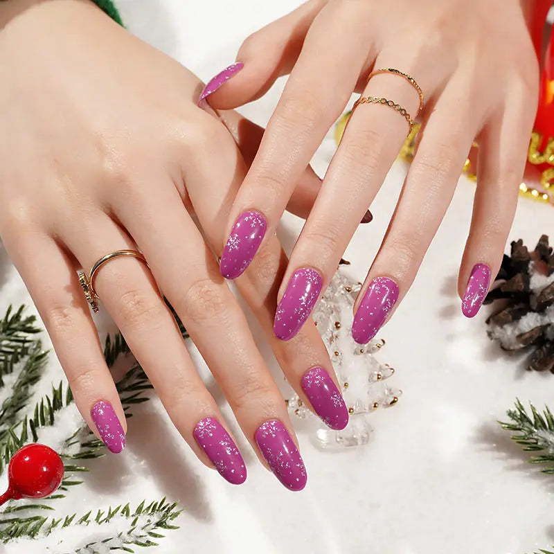 Purple Christmas nail wraps with snowflake pattern on hands with holiday decorations