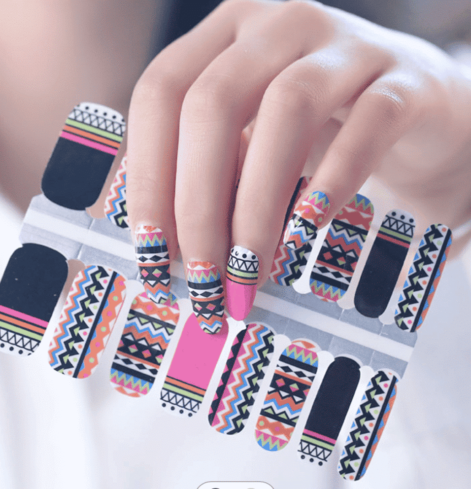 Hand wearing bright tribal geometric nail wraps with multicolour chevron and stripe patterns