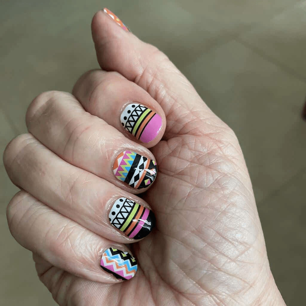 Colourful geometric nail wraps on hand featuring tribal chevron patterns in pink and blue