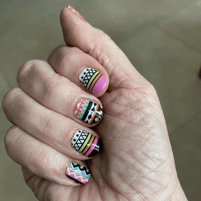 Colourful geometric nail wraps on hand featuring tribal chevron patterns in pink and blue