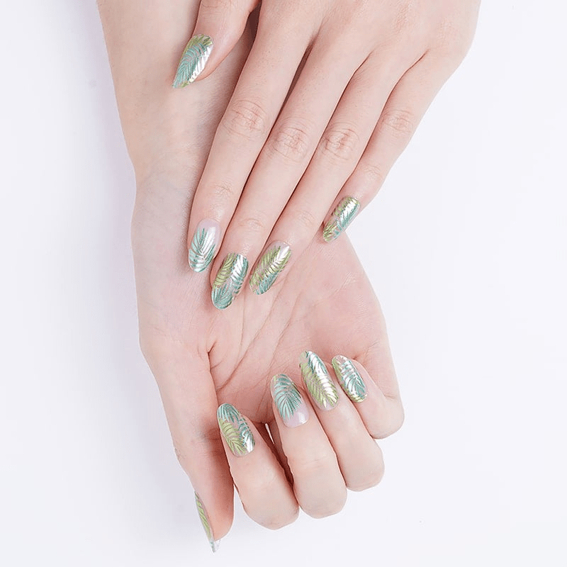 Two hands displaying green tropical fern nail wraps botanical manicure design