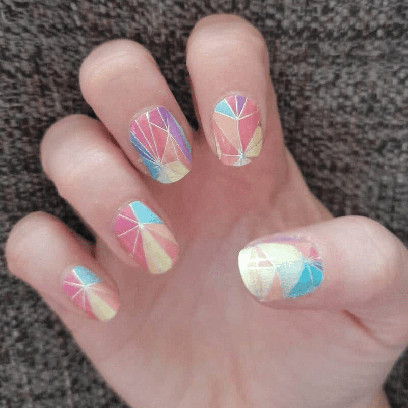 Hand wearing kaleidoscope nail wraps with geometric rainbow patterns for colourful at-home manicure