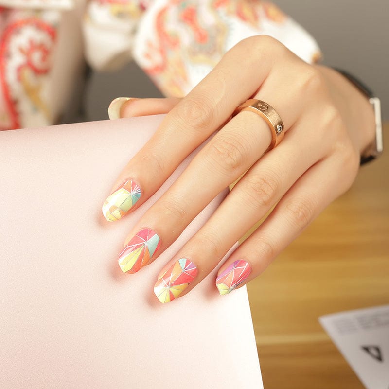 Hand wearing colourful kaleidoscope geometric nail wraps with rainbow gradient patterns