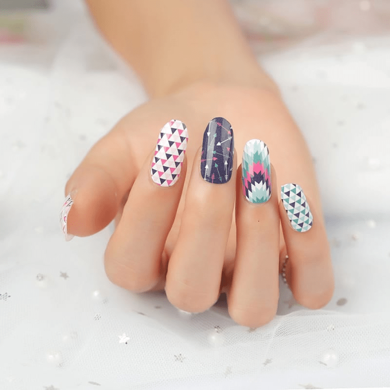 Hand displaying mixed geometric nail wraps with triangles and chevron nail art designs