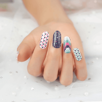 Hand displaying mixed geometric nail wraps with triangles and chevron nail art designs
