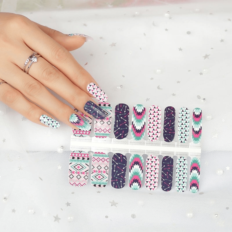 Hand wearing geometric non-UV nail wraps with tribal patterns in pink, navy, turquoise and white