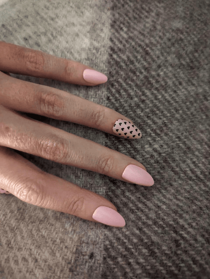 Glossy pale pink nail wraps, almond shape, one accent nail with tiny black hearts