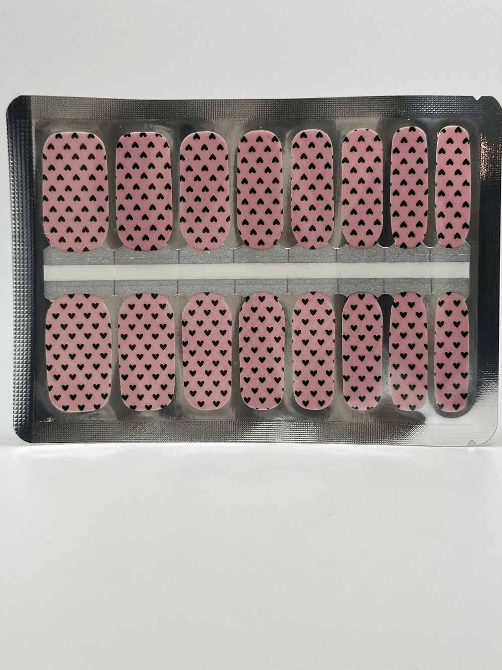 Non-UV nail wraps sheet with pink background and black heart pattern for at-home manicure