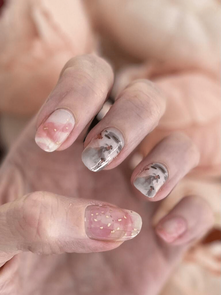 Hand displaying koi fish nail wraps featuring pink and grey watercolour nail art