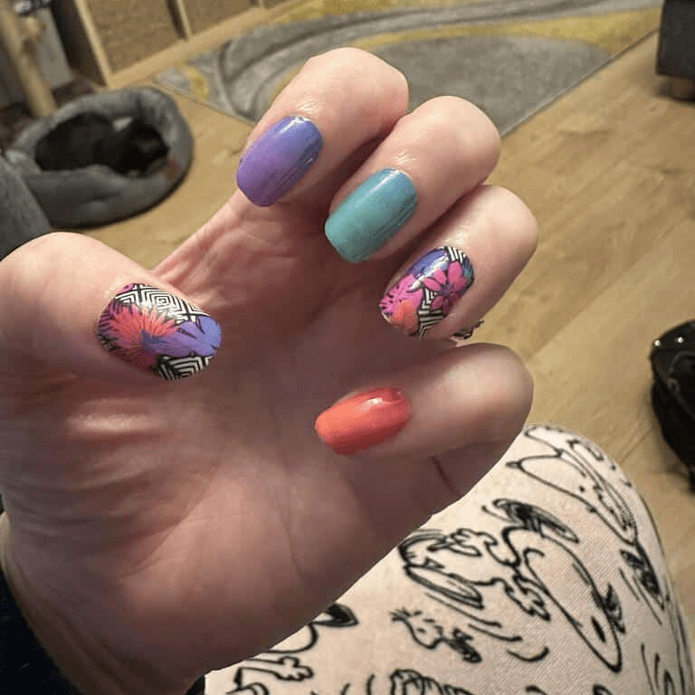 Hand displaying vibrant geometric nail wraps in purple teal orange with tropical floral patterns