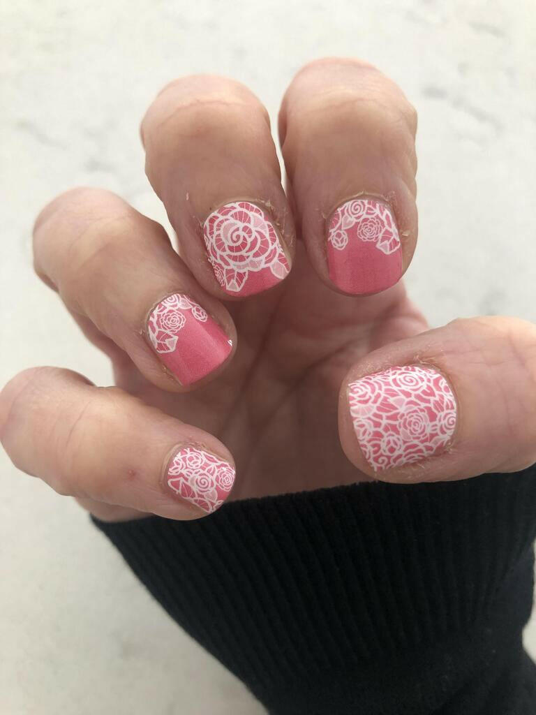 Pink nail wraps with white lace-style rose floral pattern, glossy finish