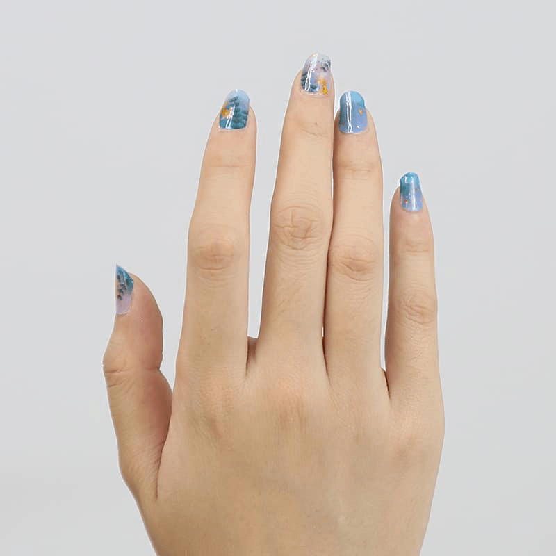 Blue floral nail wraps on hand displaying delicate botanical pattern manicure design