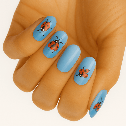 Hand showing blue nail wraps with cute red ladybird design for whimsical manicure
