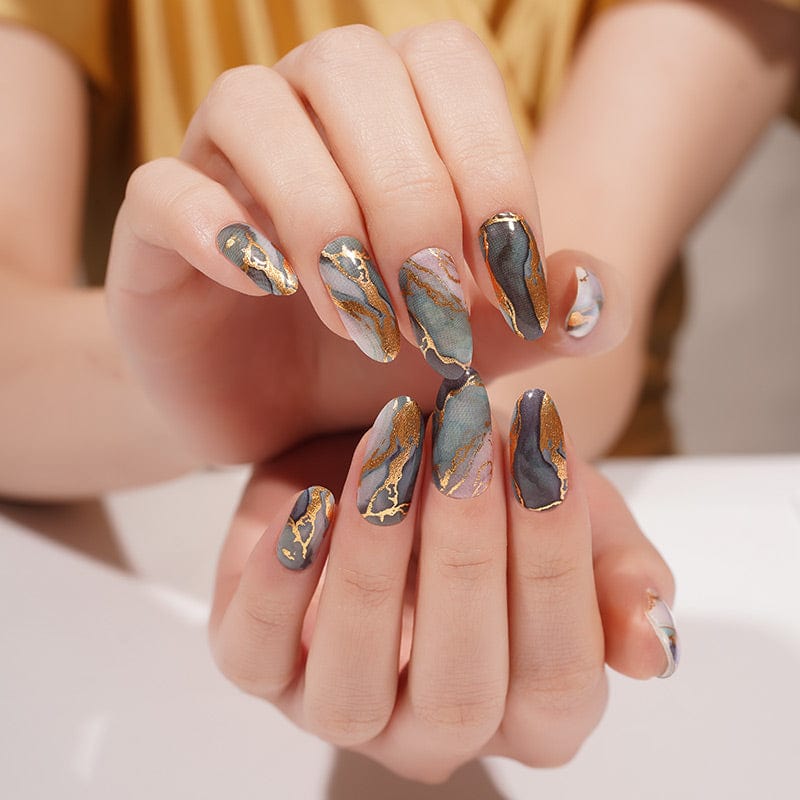 Green marble nail wraps with gold veining on hands showing at-home manicure