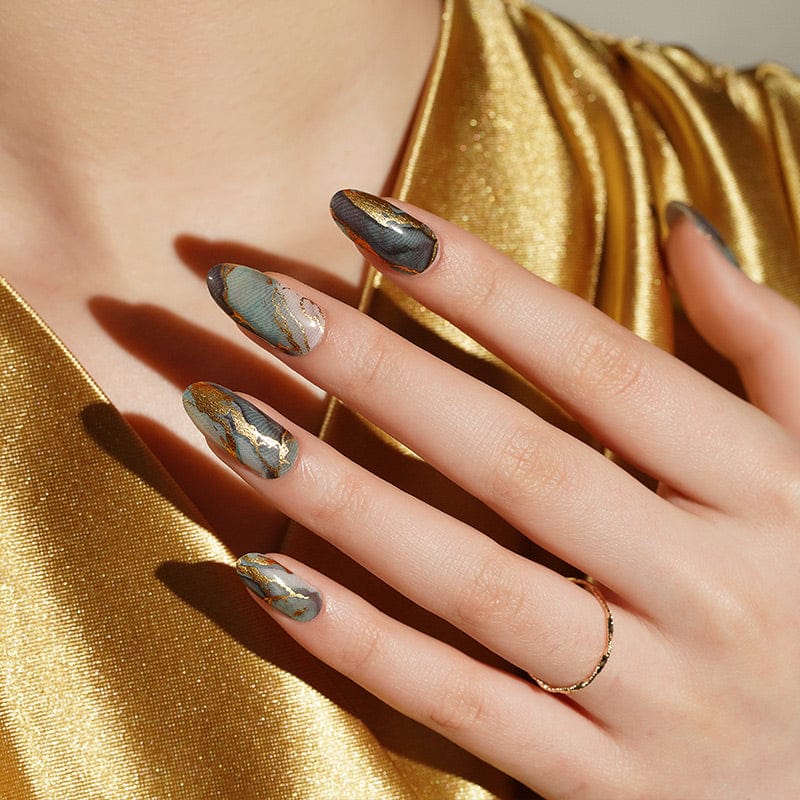 Almond shaped nails with green marble nail wraps featuring gold veined stone design