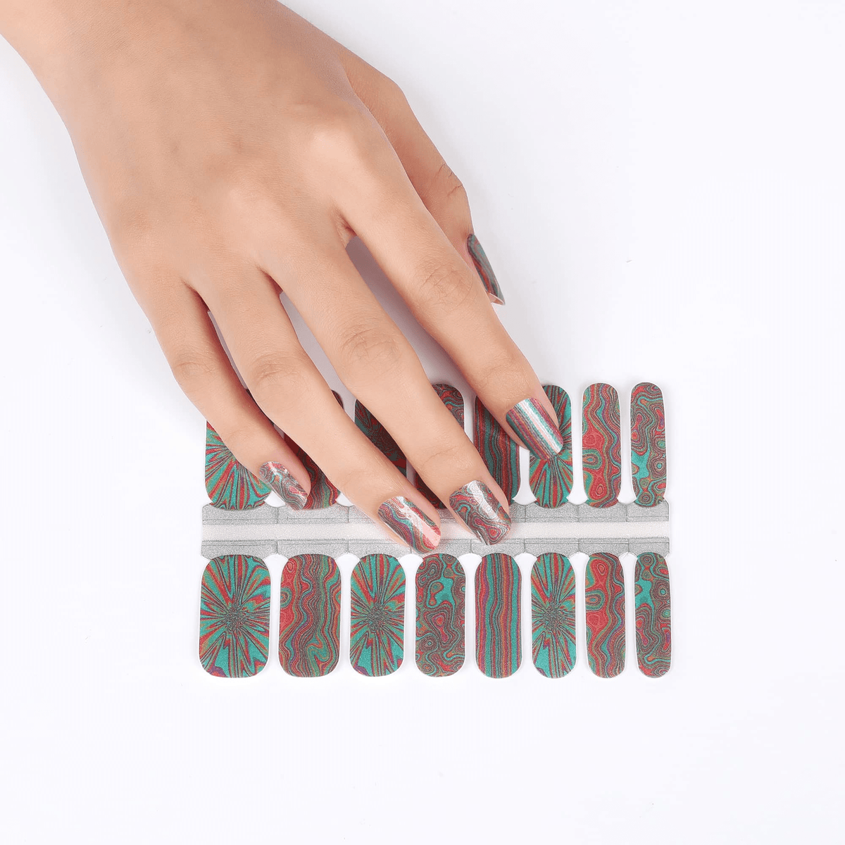 Hand placing multicoloured nail wraps with trippy swirl patterns for at-home manicure