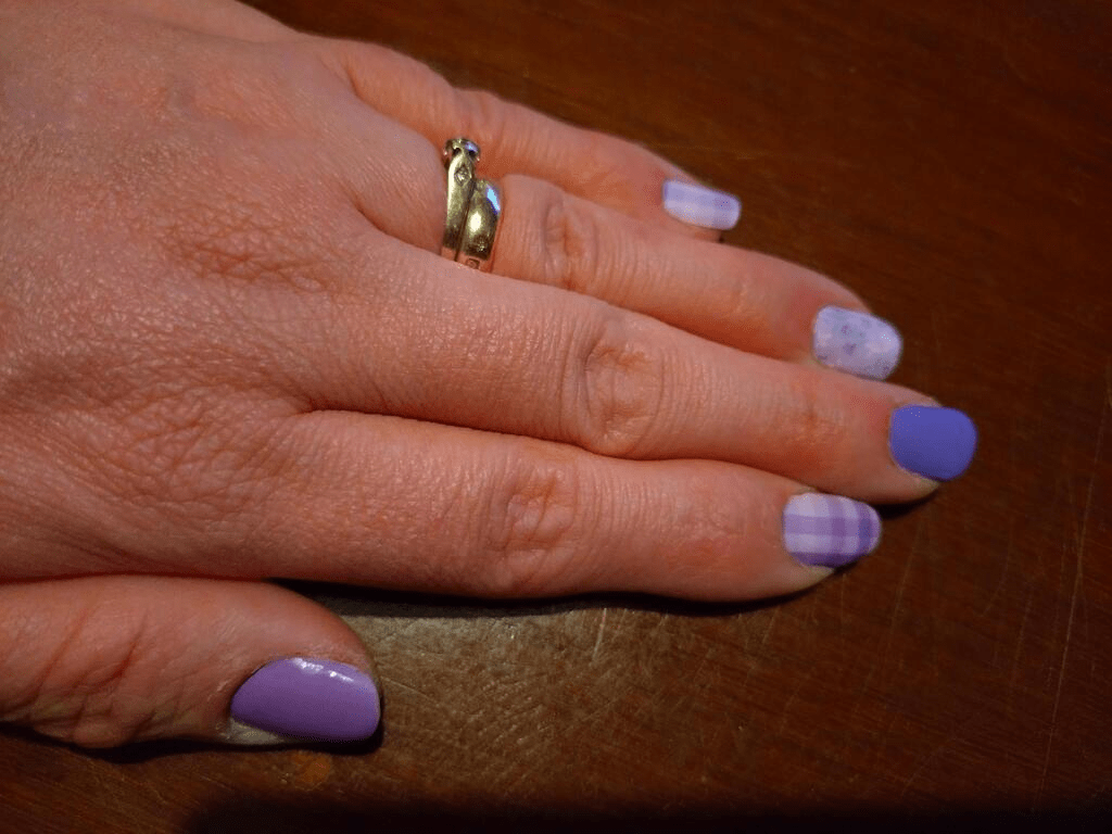 Hand wearing purple lavender nail wraps with plaid pattern manicure design