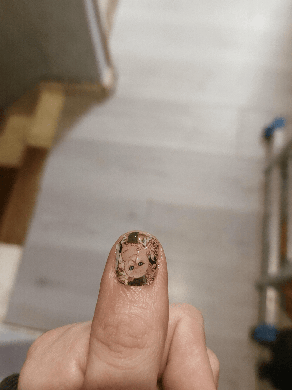 Close-up of single nail with cat and floral nail wrap design