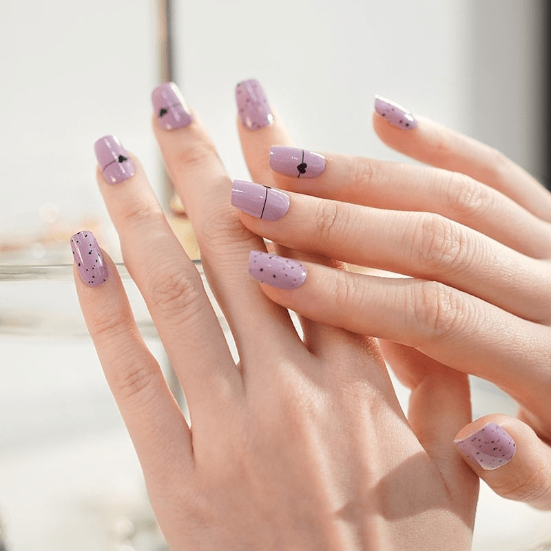 Lilac glossy nail wraps with fine black line and heart accents, speckled tips