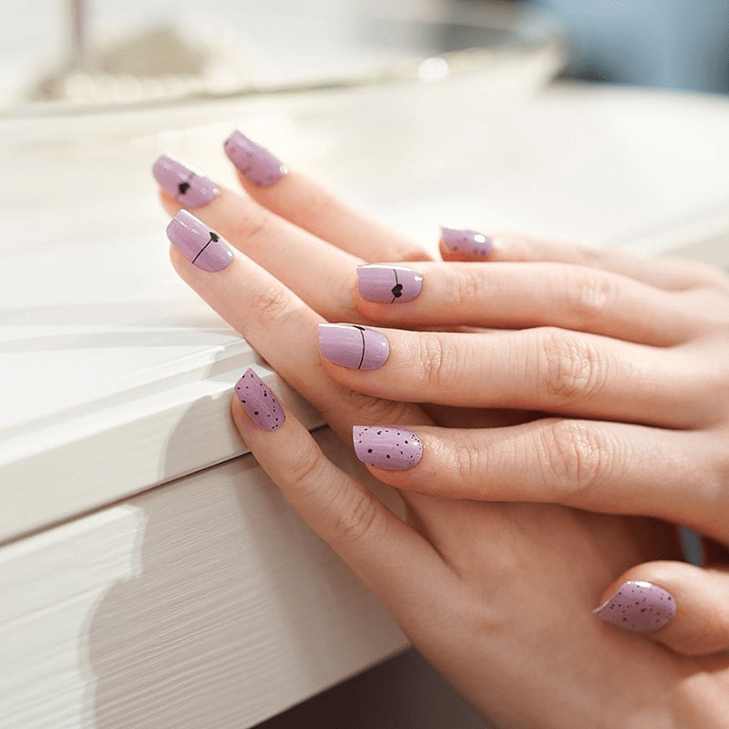 Hands displaying pink nail wraps with black polka dot pattern romantic nail art design