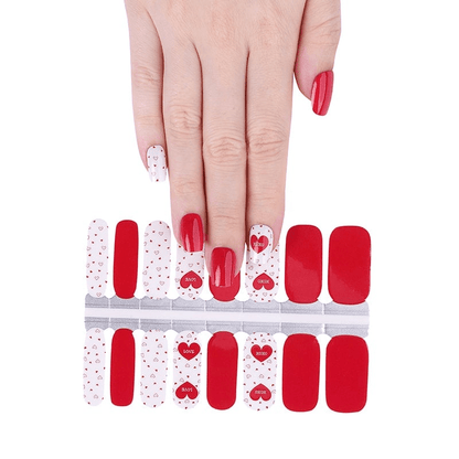 Hand showing red and white heart pattern nail wraps applied for romantic nail art