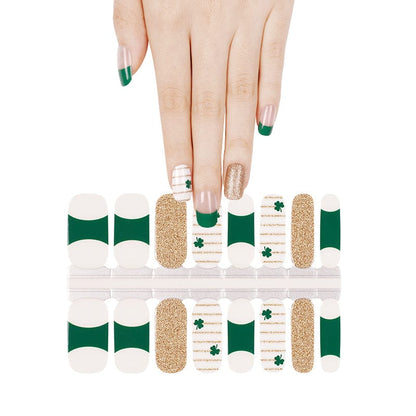 Green and gold shamrock nail wraps with glitter accents on hand for St Patrick's Day manicure
