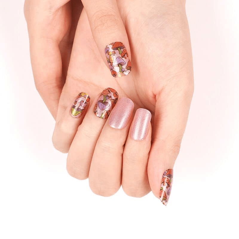 Hands showing botanical nail wraps with pink mushroom and toadstool design